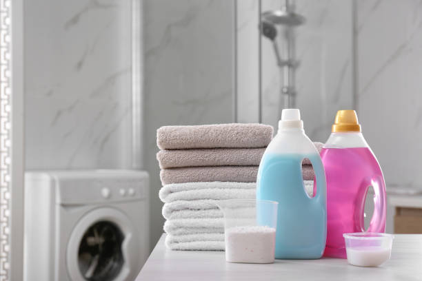 Stack of folded towels and detergents on white table in bathroom